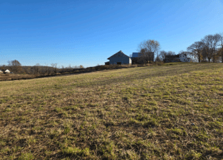 autumn cut field with farm houses in distance on hill